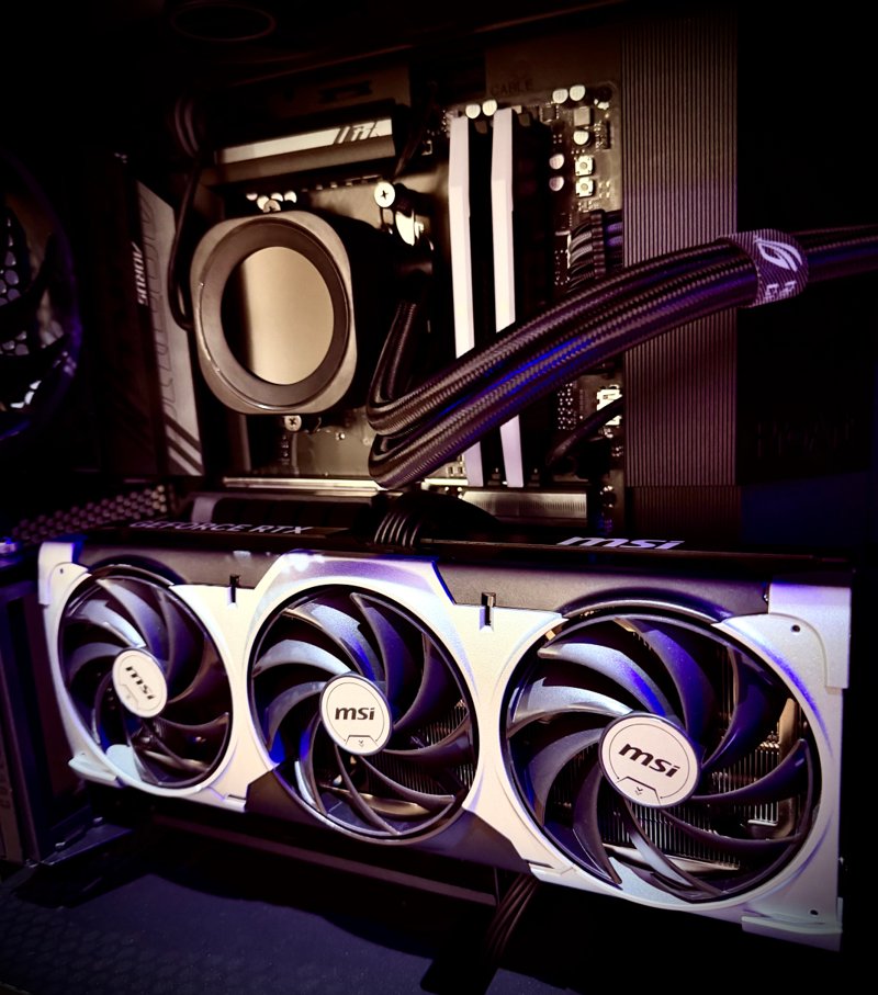 Close-up of a black gaming PC with a triple-fan MSI graphics card and liquid cooler